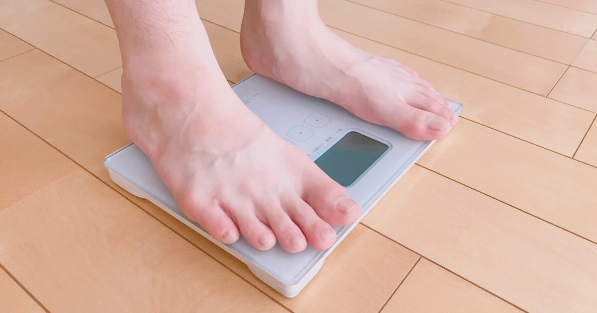 体組成計に乗って体重を測定する男性の足元